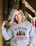 Woman wearing a cozy Christmas sweatshirt that says ‘Tree Tops Glisten and Children Listen,’ styled for a casual holiday outfit.